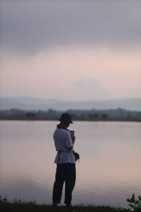 Rear view of man looking at lake against sky