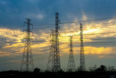 Low angle view of electricity pylon against sky during sunset