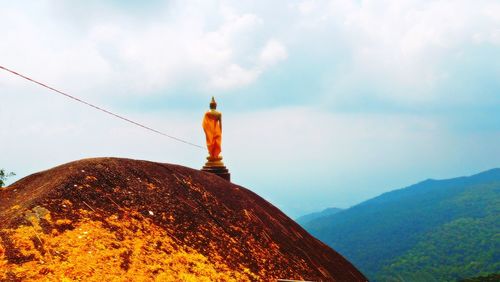 Rear view of man standing on mountain against sky
