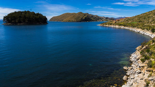 Scenic view of sea and mountains against blue sky