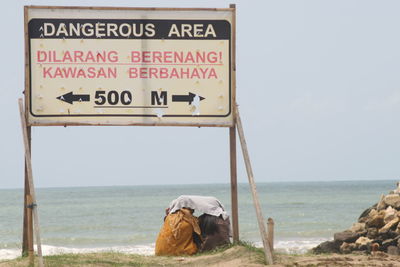 Information sign on beach against clear sky