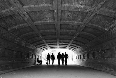 Rear view of people walking in tunnel