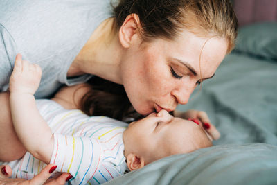 Close-up caring mother kisses her newborn baby. gentle parenting, hugs and cuddles.