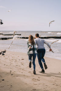 Close up of couple running near the sea and looking to each other.