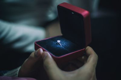 Close-up of cropped couple holding ring in jewelry box