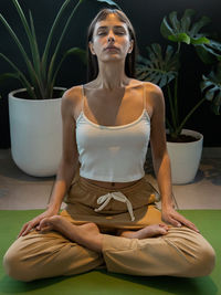 Portrait of young woman sitting on floor at home doing yoga