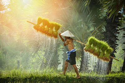 Side view of shirtless man walking on field against sky