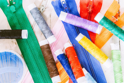 Close-up of colorful thread spools and zippers on table