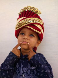 Cute boy wearing headwear looking up against wall