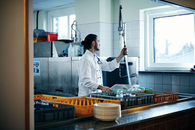 Chef looking at window while washing dishes in kitchen