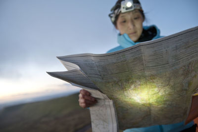 Female hiker reading hiking map on pen y fan in wales at sunrise