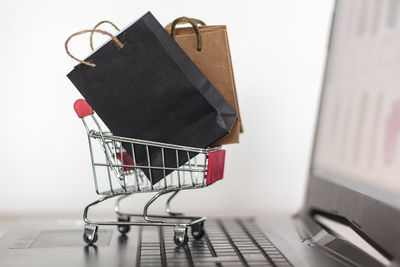 Close-up of small paper bags in shopping cart on laptop