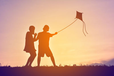 Silhouette of children flying kite