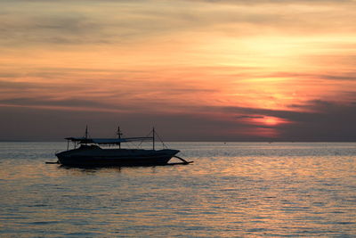 Silhouette boat in sea against sky during sunset