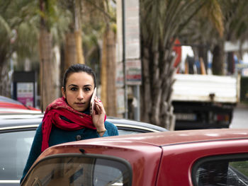 Portrait of woman talking over smart phone while standing in city