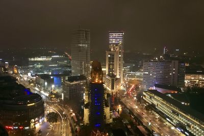 High angle view of illuminated street amidst buildings in city at night
