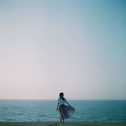 Full length of woman standing on beach against clear sky