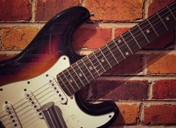 Close-up of guitar against brick wall