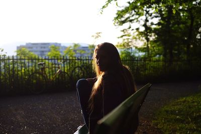 Portrait of young woman sitting on bench at park