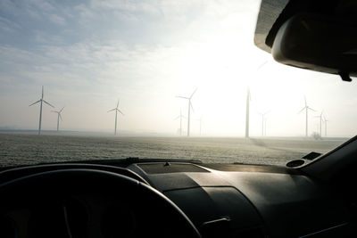 Wind turbines on landscape seen through car windshield