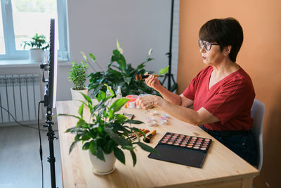 Side view of young woman using mobile phone while sitting on table