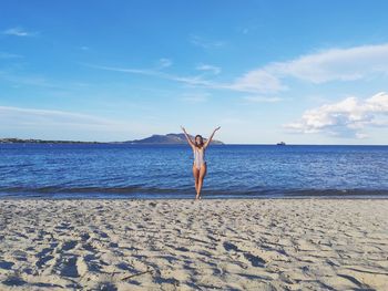 Full length of woman standing on beach against sky