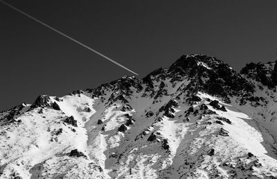 Low angle view of snowcapped mountains against clear sky