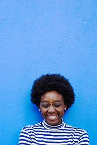 Portrait of smiling young man standing against blue wall