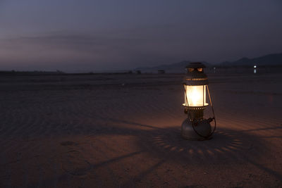 Light trails on sand at beach against sky at night