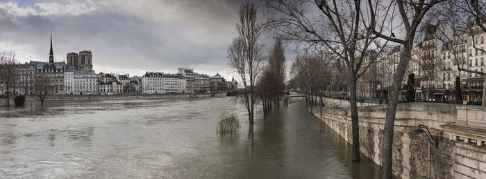 Buildings by river against sky in city