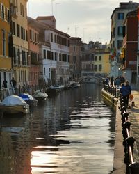 Boats moored in canal amidst buildings in city