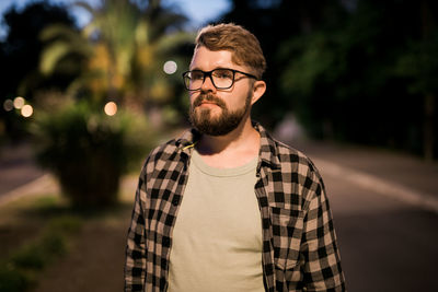 Portrait of young man standing against trees