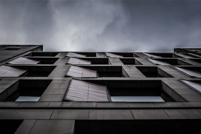 Low angle view of modern building against cloudy sky