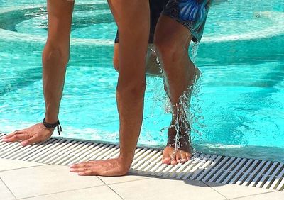 Low section of woman standing in swimming pool