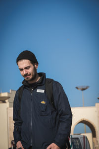 Young man standing against blue sky