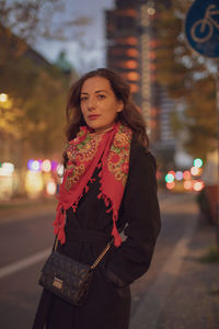 Portrait of young woman standing on street at night