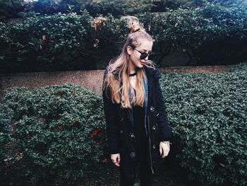 Young woman standing by plants