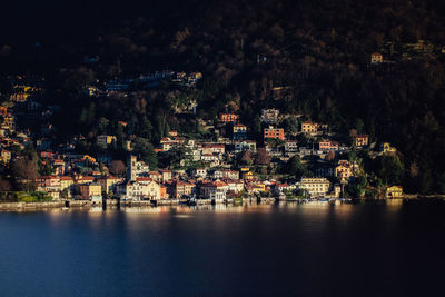 Town by sea against sky in city at night