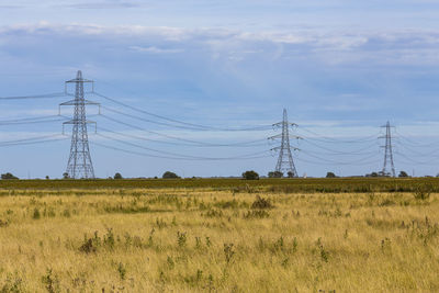 Electricity pylon on field against sky