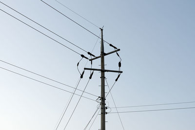 Low angle view of electricity pylon against clear sky