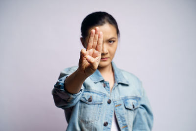 Portrait of young woman standing against gray background