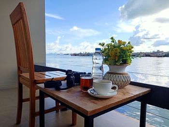 Potted plant on table by sea against sky