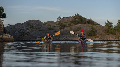 People in kayaks on sea against sky