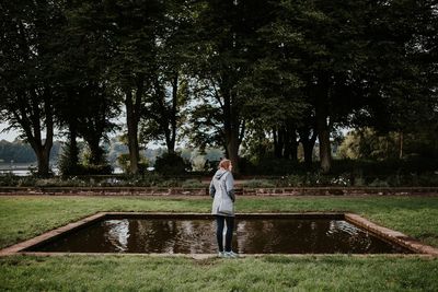 Woman standing by pond at park