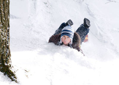 Portrait of boy tobogganing on snowy field