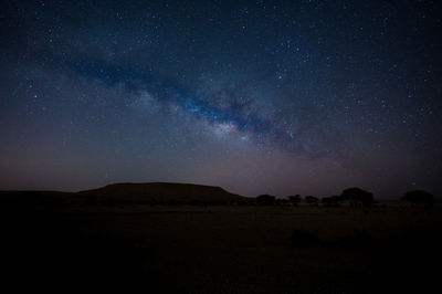 Scenic view of landscape against sky at night milky way