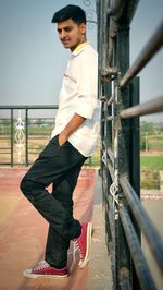 Portrait of young man standing on railing