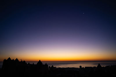 Silhouette buildings against clear sky during sunset