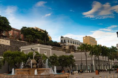 Statue by buildings against sky in city