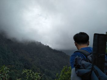 Rear view of man looking at mountains against sky